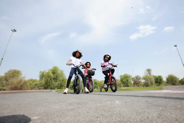 Kids riding Mogoo bikes toward the camera in a Dubai park