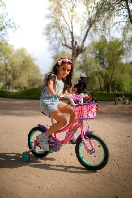 Girl riding a pink Mogoo bike with training wheels