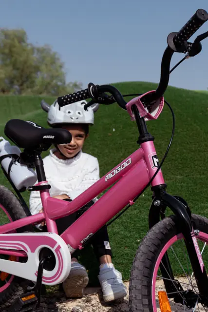 Girl in a Mogoo helmet with her pink bike