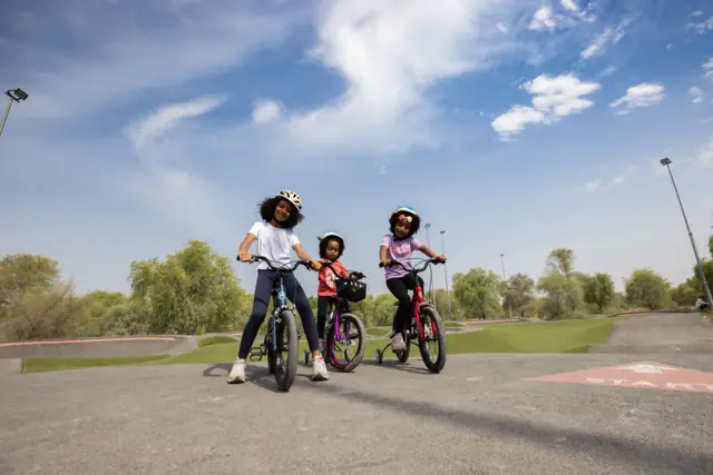 Mother and daughters riding Mogoo bikes under a big sky